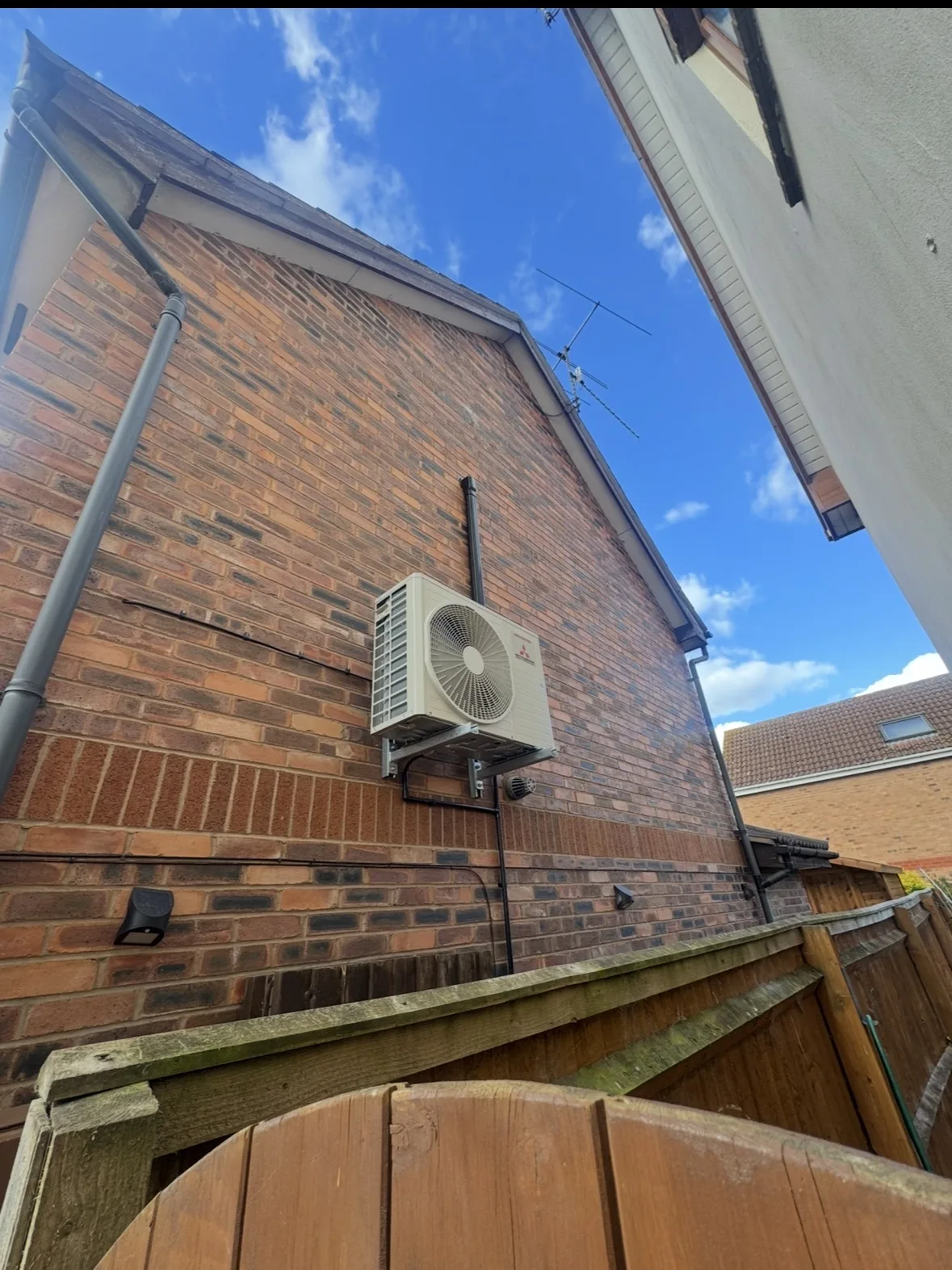 External air conditioning condenser neatly mounted on a brick wall by Aervue